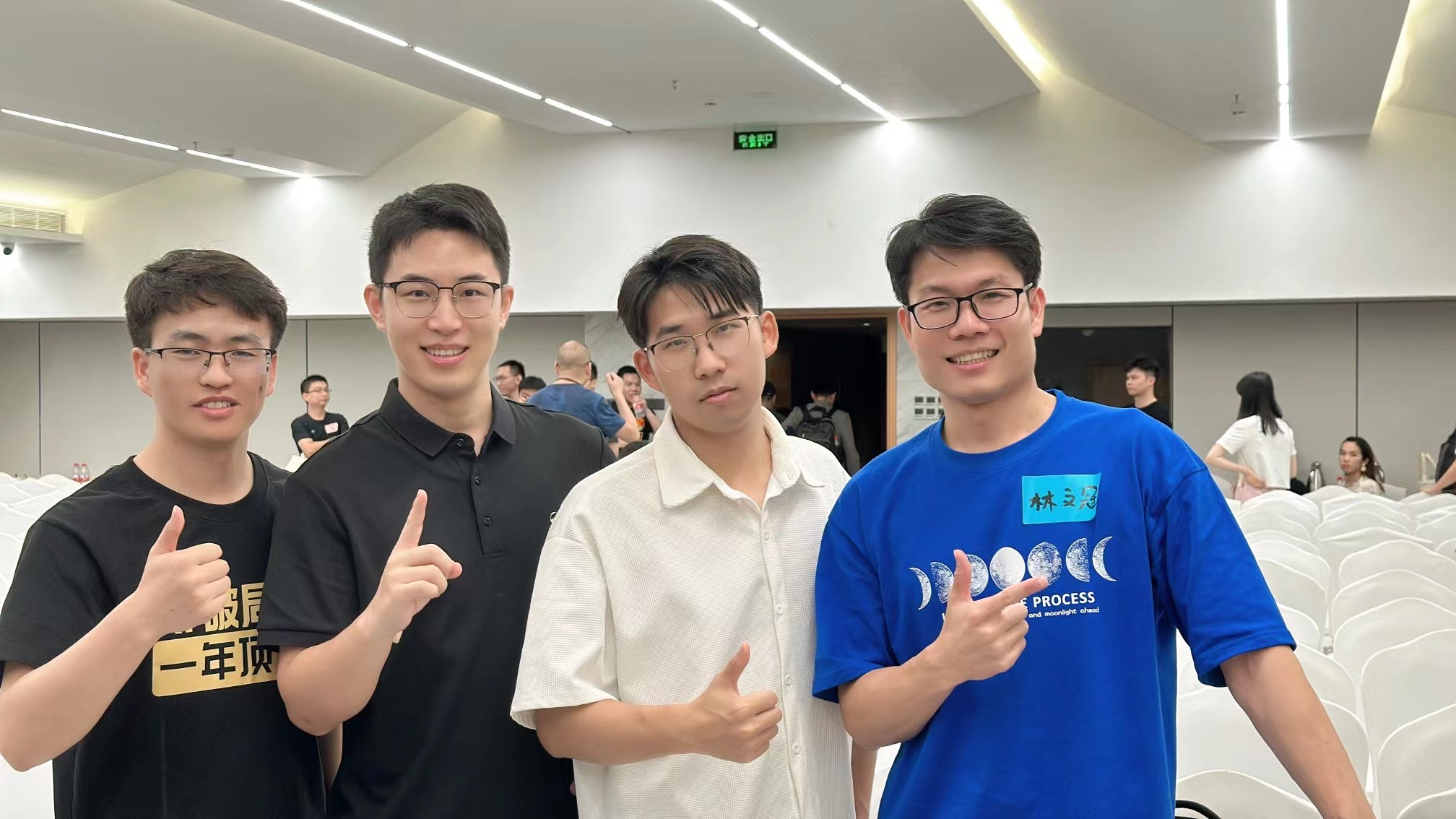 图片展示了四位男士在室内合影。左侧两位男士穿着黑色上衣，中间一位穿白色上衣，右侧一位穿蓝色印有“PROCESS”字样的T恤。他们面带微笑，其中两位竖起大拇指，背景为浅色墙面和座椅，天花板上有“SIP”标识。此图与上文提到的“和云猫、肖肖老师一起做训练营教练，我们发挥各自的优势，帮助学员创造了60万+的GMV”相呼应，可能是教练团队合影，体现了合作共创的氛围。