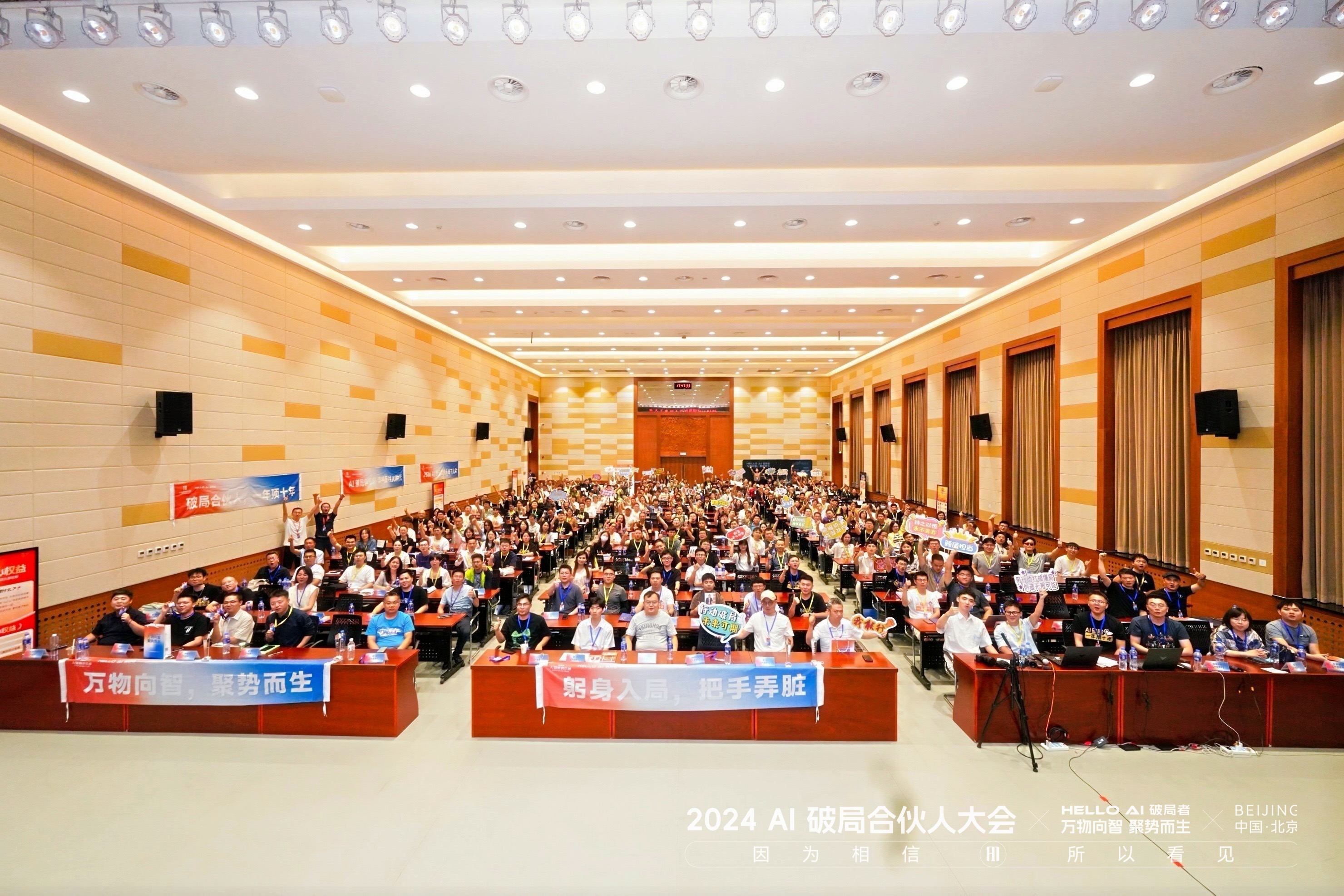 图片展示的是2024 AI破局合伙人大会现场。会场内座无虚席，观众席上坐满了人，部分人举着写有“万物向善，顺势而生”“躬身入局，牵手弄脏”等标语的牌子。会场前方有红色的讲台，上方悬挂着“2024 AI破局合伙人大会”字样。该图片与文档中作者分享在破局行动家大会分享数字人AIP成长经历的内容相关，直观呈现了大会盛况。