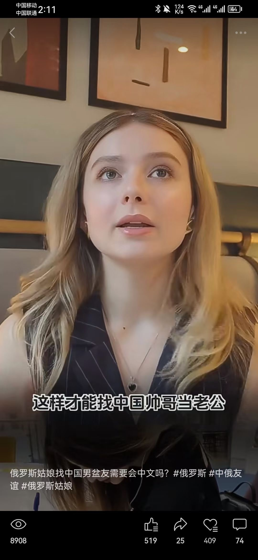 图片展示了一位金发俄罗斯美女，她戴着耳麦，身穿黑色条纹服装，正对着镜头说话。画面下方配有字幕“这样才能找中国帅哥当老公”，底部还有视频话题标签，如“俄罗斯姑娘找中国男盆友需要会中文吗？#俄罗斯 #中俄友谊 #俄罗斯姑娘”。视频播放量为8908，点赞数519，转发25，收藏409，评论74。该图片与文档上下文相关，是文档中提及的“外国美女讲中文”视频的截图示例。