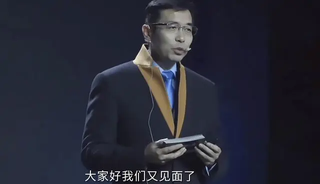 图片展示的是商汤科技年会上，以数字人技术“复活”的汤晓鸥的形象。他身着深色西装，佩戴金色领带，手持黑色物品，背景为深色。画面下方有白色字幕“大家好我们又见面了”。该图片与上下文紧密相关，上下文介绍了汤晓鸥数字人在年会上以数字化形象与参会者交流，惟妙惟肖且生动幽默，此图正是这一场景的呈现。